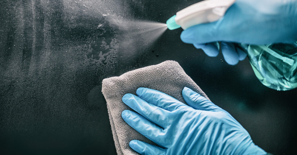 Image a person with gloved hands cleaning a surface.