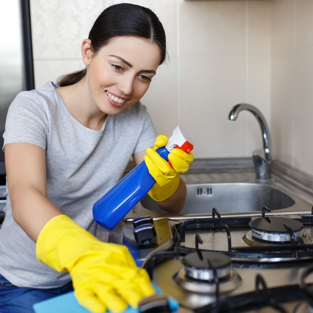 woman smiling while cleanings stove